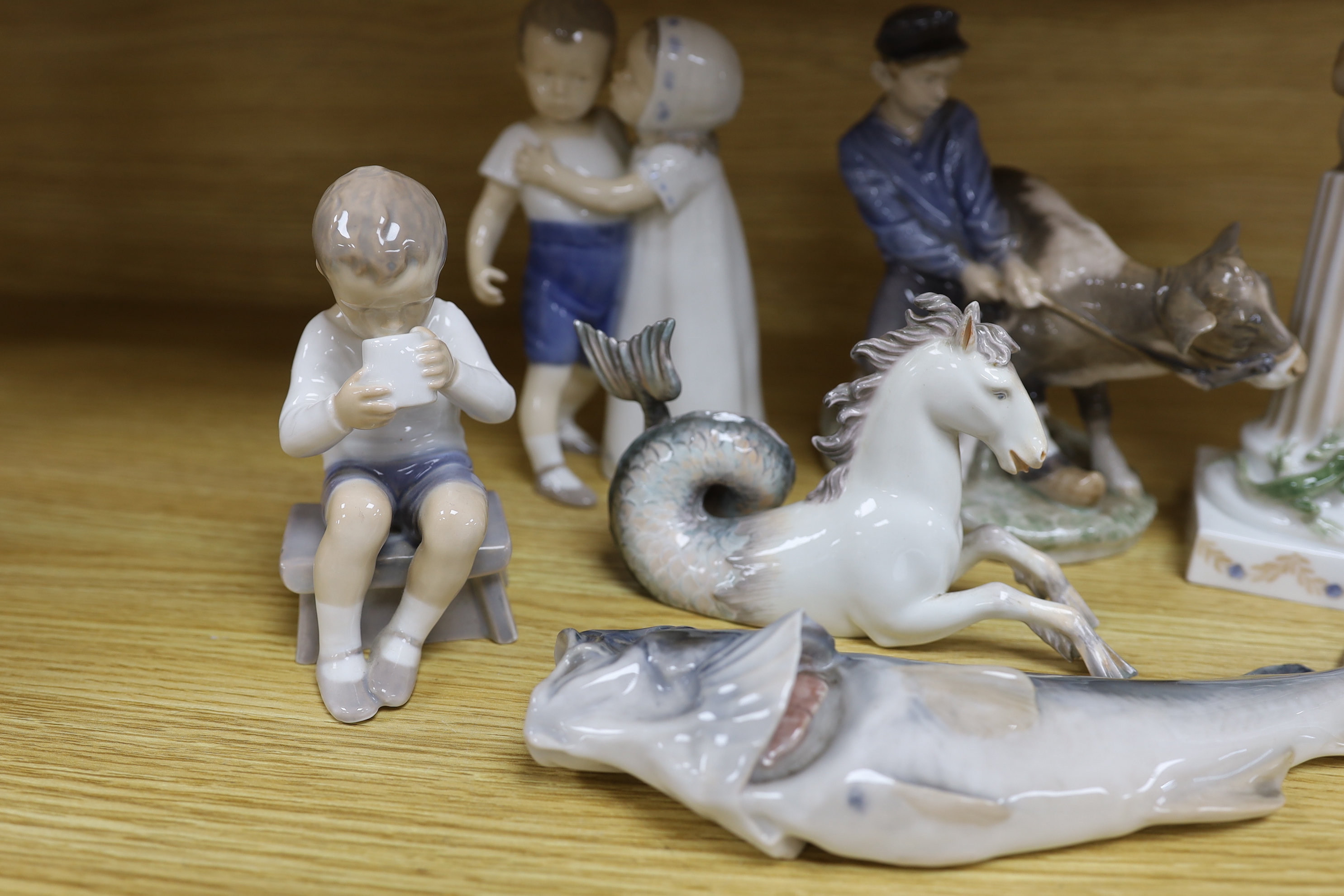 Seven mixed Royal Copenhagen models including children, fish, a fawn, a sailor, a cow and a seahorse (hippocampus), the largest 23cm high